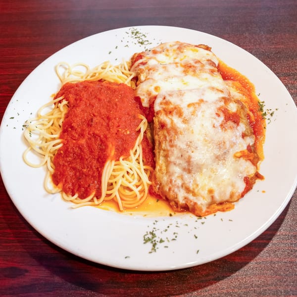 Chicken parmesan with melted cheese and spaghetti with red sauce on a white plate.