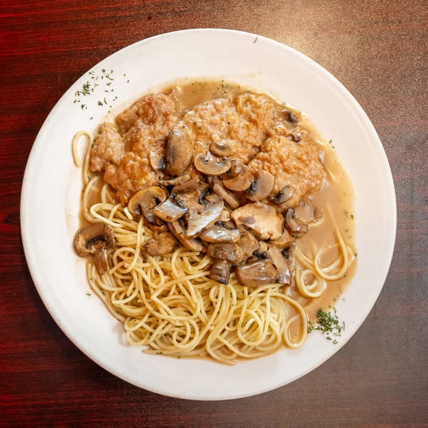 Chicken Marsala with mushrooms and spaghetti on a white plate, viewed from above.